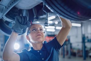Portrait,Shot,Of,A,Female,Mechanic,Working,Under,Vehicle,In